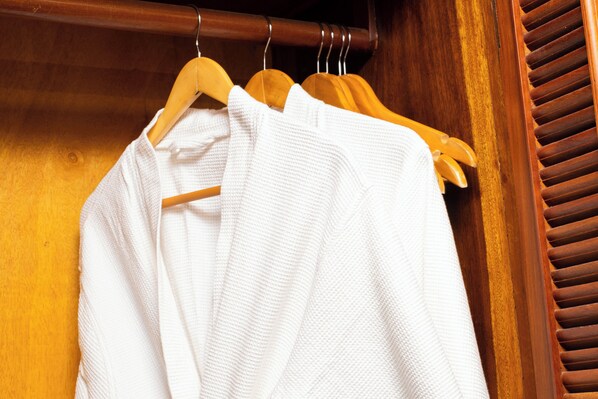 A wooden closet with a wooden door and a wooden hanger rack holding white garments. - Angkor Land Urban Boutique (Siem Reap)