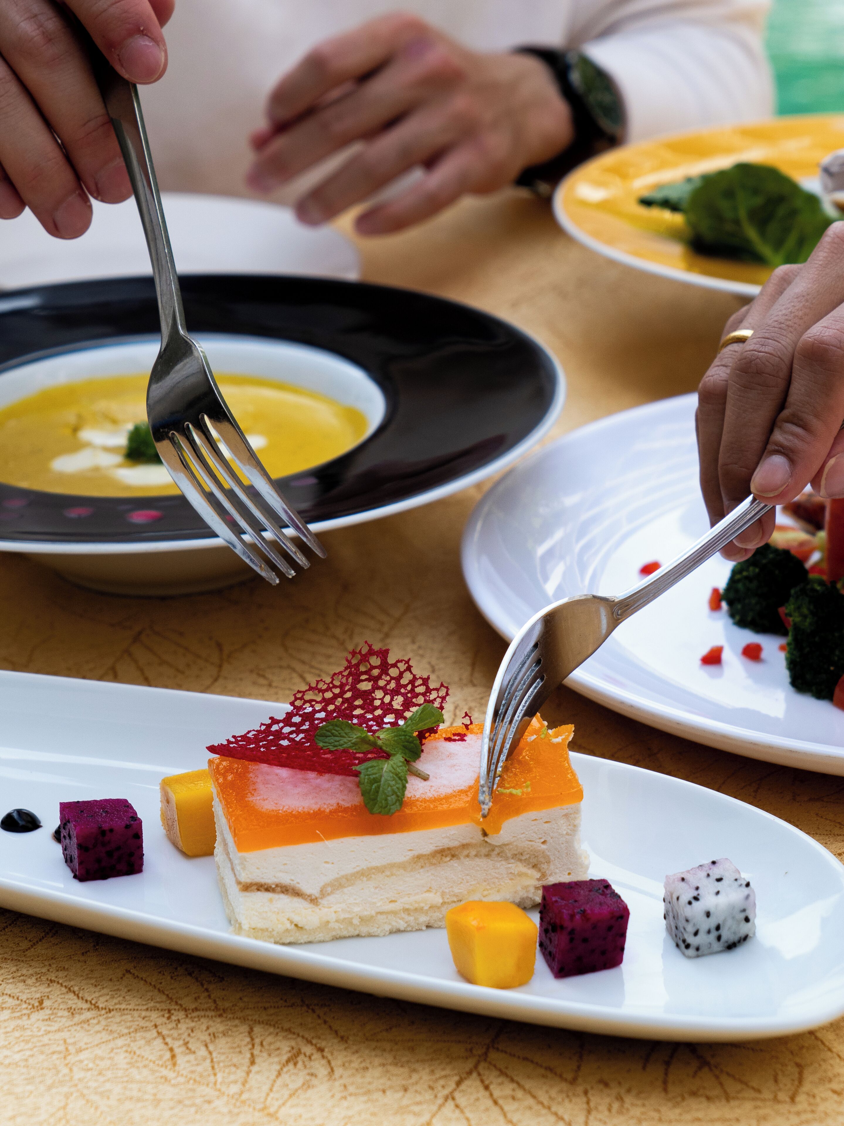 A dessert plate with a slice of cake, fruit, and a mint garnish.