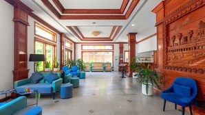 Un vestíbulo espacioso con techos altos, grandes ventanales y una zona de estar central con sofás y sillones.