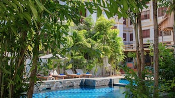 A pool area with lounge chairs and a stone wall.