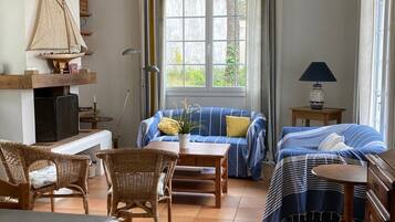 A cozy living room with a sofa, chairs, a table, a TV, and a sailboat model.