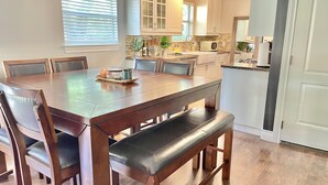 Ein Essbereich mit Holztisch und Stühlen, einer Bank und einer Küche im Hintergrund.
