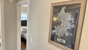 Ein Flur mit einer gerahmten Karte von Austin an der Wand, einer Tür, die zu einem Schlafzimmer führt, und einem Lichtschalter.