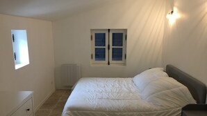 A bedroom with a bed, a dresser, a window, and a radiator. - Gîte 12 Personnes (Brem-sur-Mer)