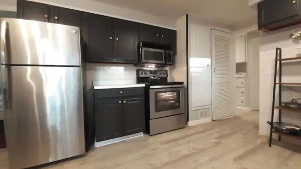 A modern kitchen with stainless steel appliances, dark cabinetry, and a microwave.