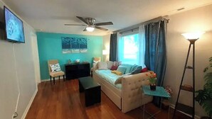 A living room with a sofa, a small table, a TV, and a ceiling fan.