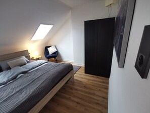 Une chambre à coucher avec un lit, une chaise, une armoire et une lucarne.