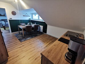 Un coin repas avec une table et des chaises en bois, une horloge au mur et une enseigne indiquant « LIDLINGSPATZ ».