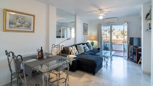 Un salon moderne avec une table à manger en verre, un canapé et un téléviseur.