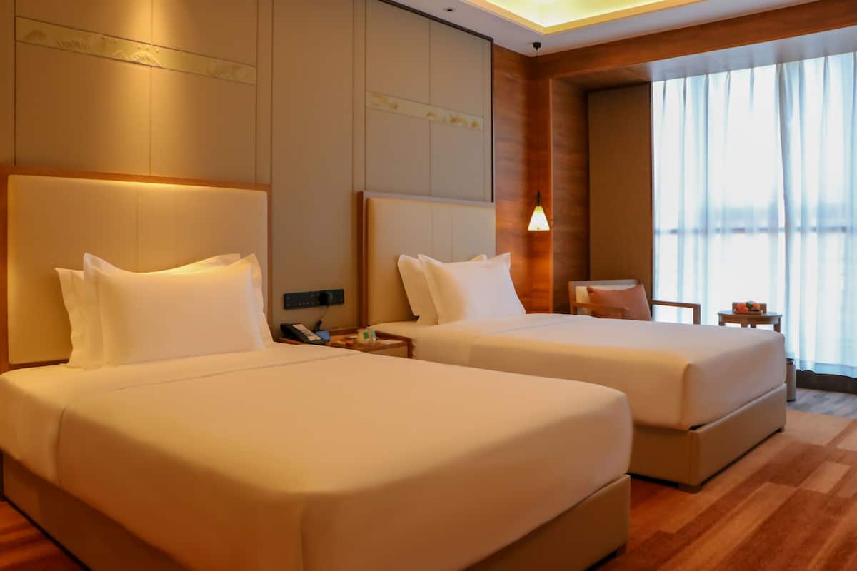 Ein Hotelzimmer mit zwei Betten, einem kleinen Tisch und einem Stuhl.