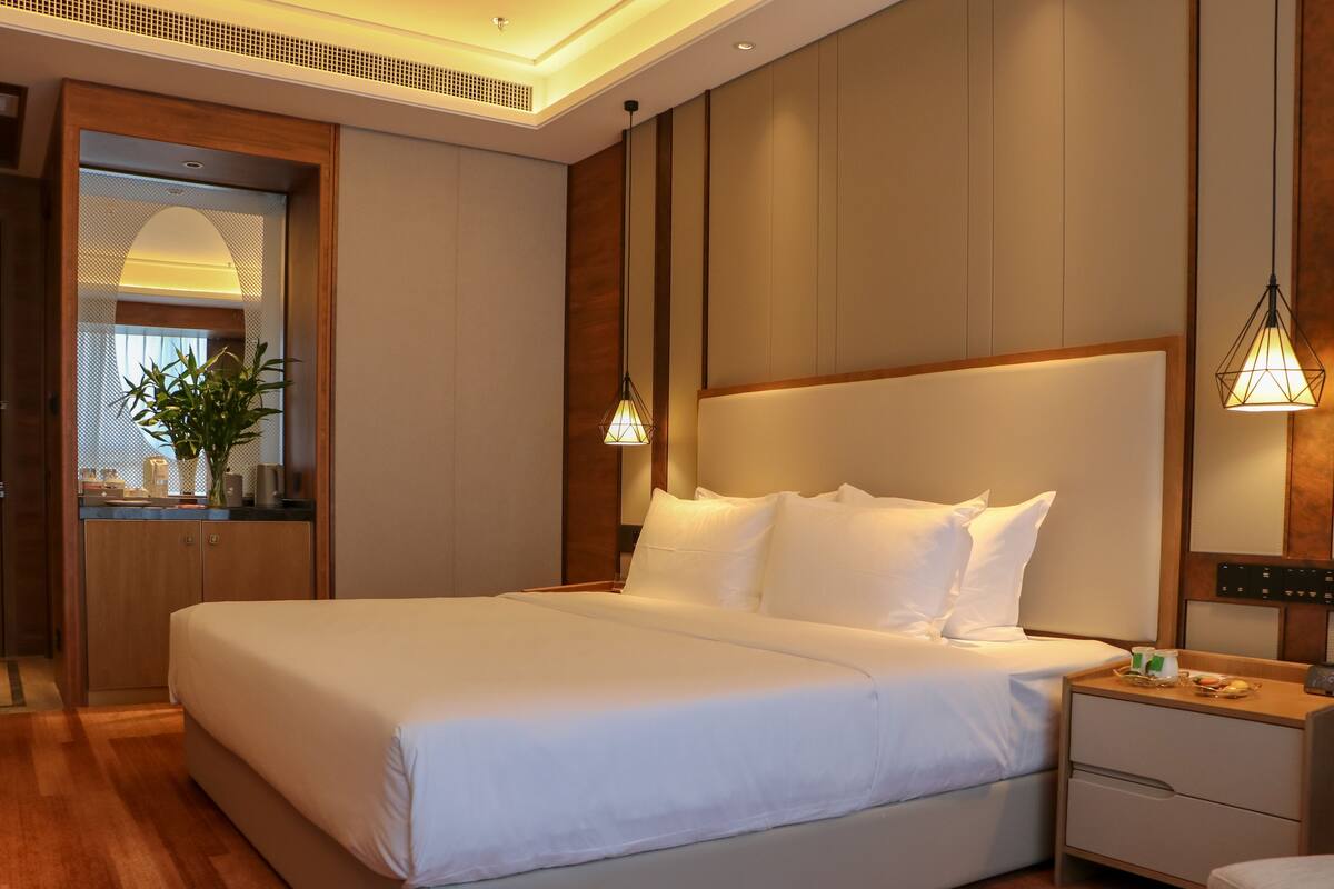 Ein Hotelzimmer mit einem großen Bett, Nachttischen, einem kleinen Schreibtisch und einem Stuhl.