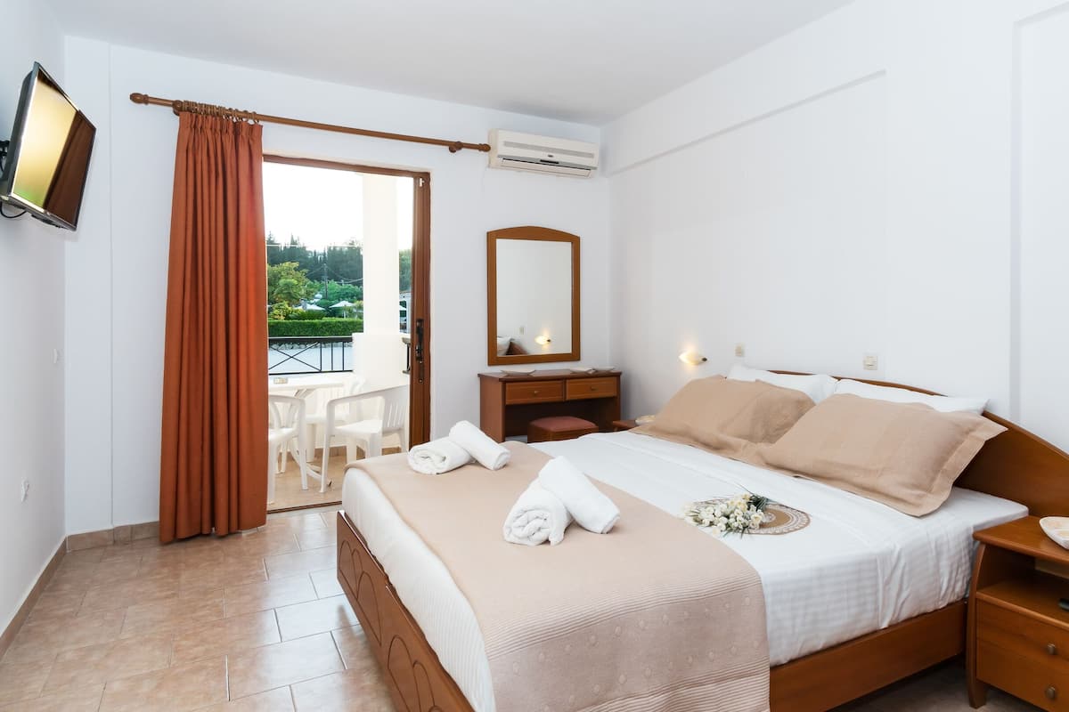 A hotel room with a bed, bedside table, a mirror, a small desk, and a chair.