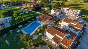 Vista aérea de un complejo turístico con varias edificaciones, una piscina y céspedes cuidados.