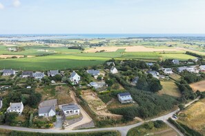 A rural landscape with houses, fields, and a body of water in the distance. - The Villa de Pen ar Menez, featuring a private spa and views of the countryside—beaches just 5 minutes away (Plouider)