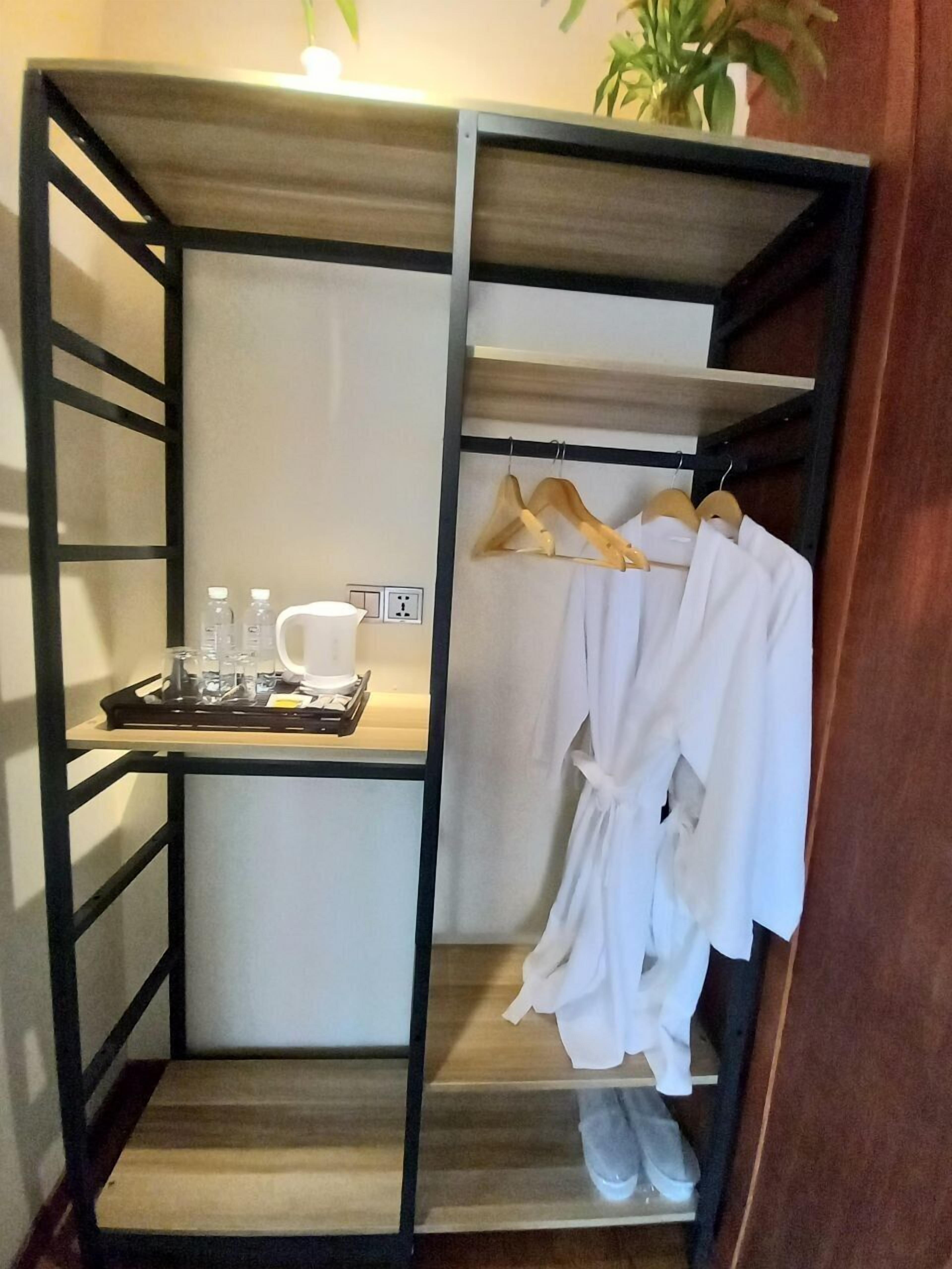 Un baño moderno y compacto con tocador de madera, un perchero con batas y una bandeja con artículos de aseo.