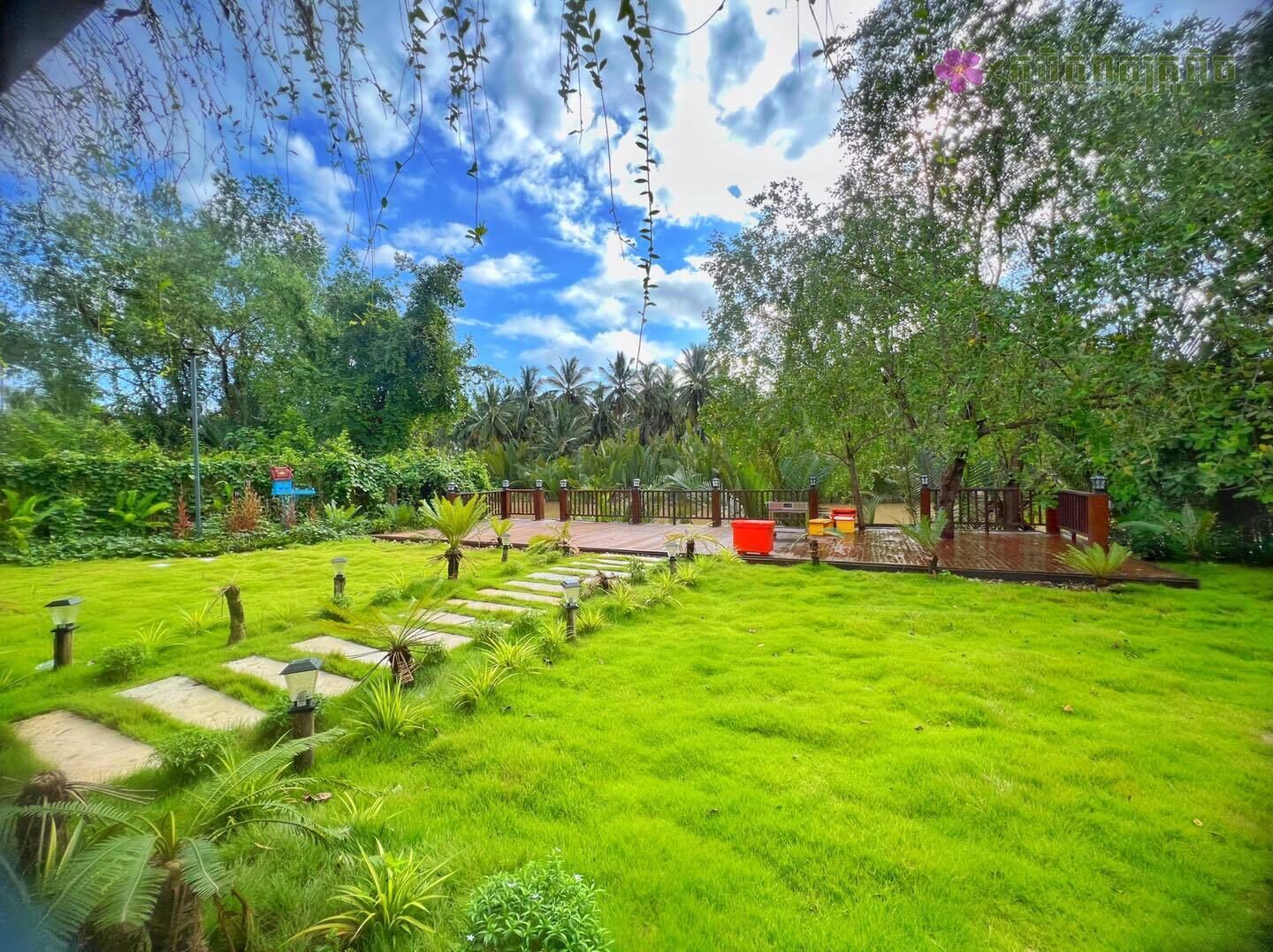 A lush garden with a paved pathway leading to a wooden deck.