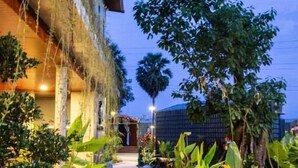 A pathway leading to a building with a water feature and potted plants. - Kampot Tropical Village (Kampot)