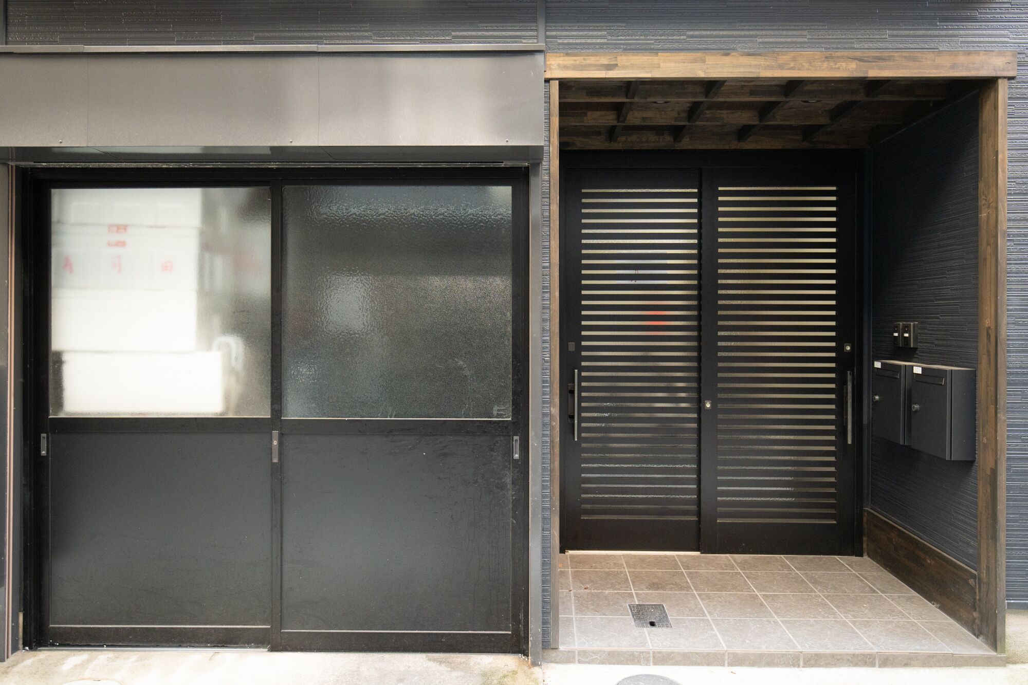 A modern building entrance with a large glass door and a metal sliding door.