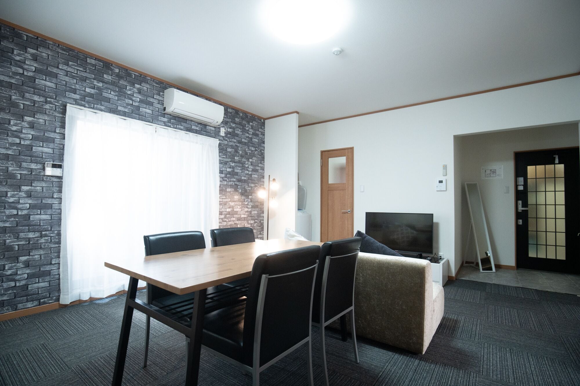 A conference room with a brick wall, a wooden table, and black chairs.