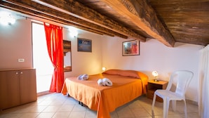 A bedroom with a bed, a chair, a nightstand, and a wardrobe. - Flower Apartment (Cefalù)