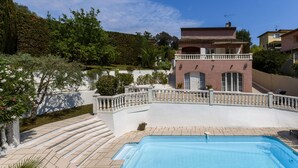 Una piscina con gradini che vi conducono, circondata da un muro bianco e un balcone.