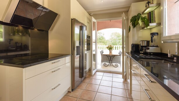 Una cucina moderna con forno integrato, elettrodomestici in acciaio inossidabile e una porta scorrevole che dà su un balcone.