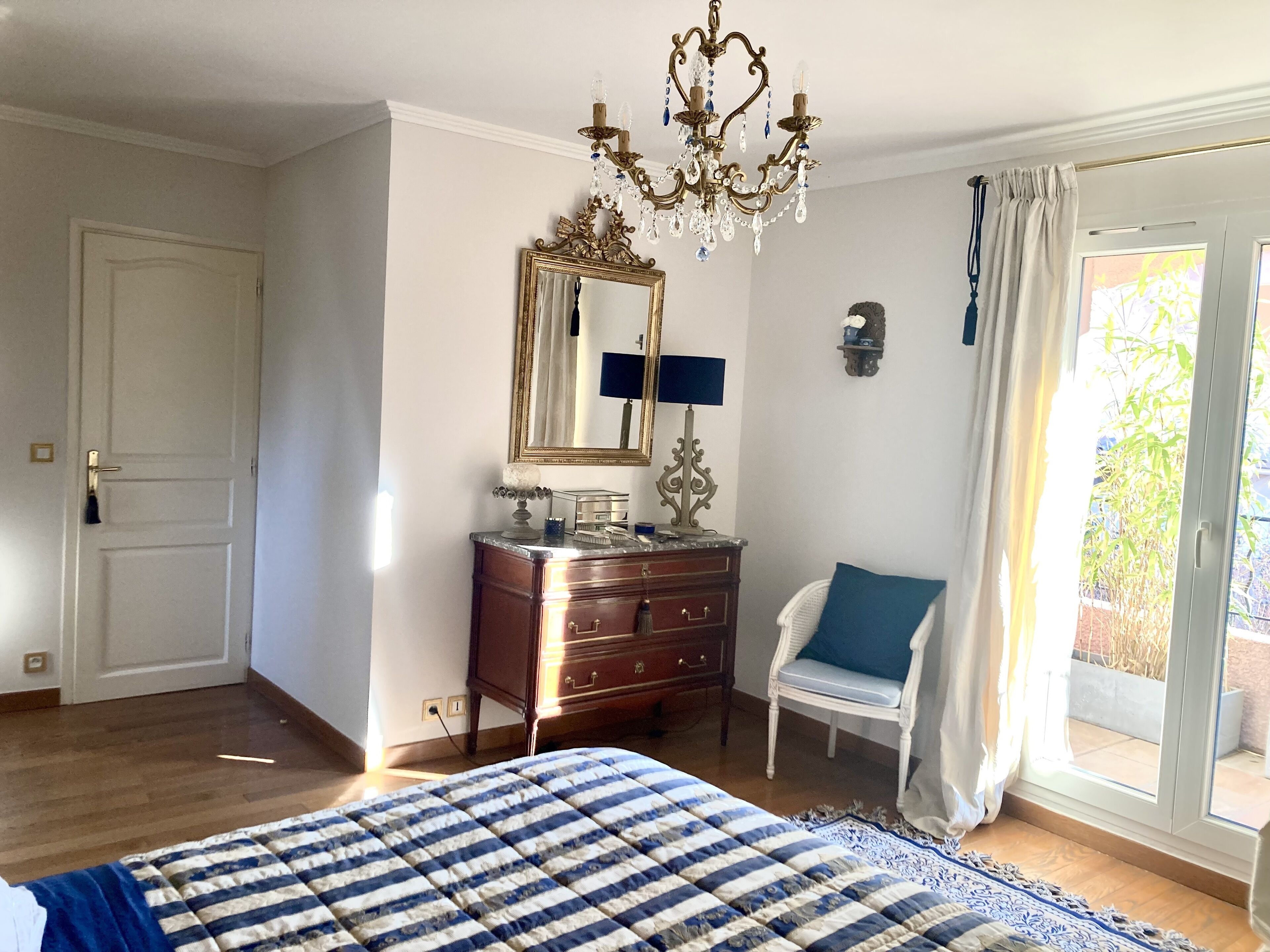 Ein Schlafzimmer mit Bett, Schminktisch, Stuhl und einem großen Spiegel.