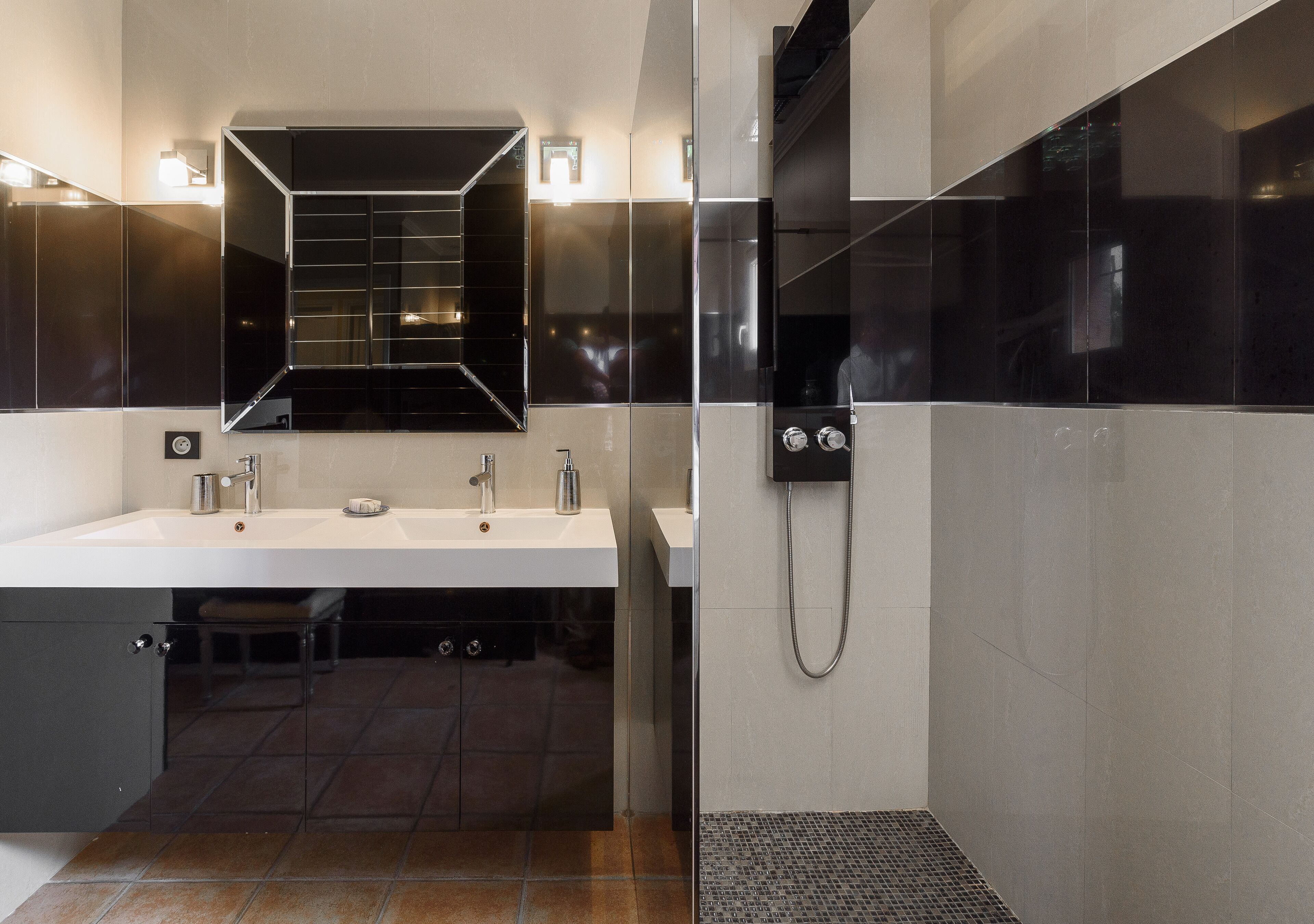 A modern bathroom with a large mirror, two sinks, and a shower.