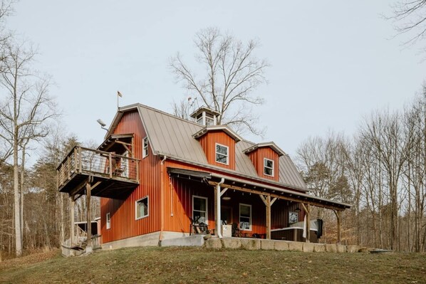 A large, single-story red barn with a porch and a small attached structure.