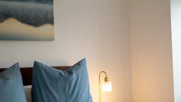 Ein Hotelzimmer mit einem Bett, zwei Kissen, einem Nachttisch mit Lampe und einem Bild an der Wand.