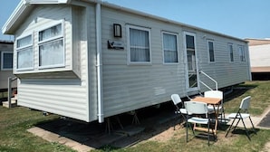 Une maison mobile dotée d’un patio couvert, d’une table à manger et de chaises.