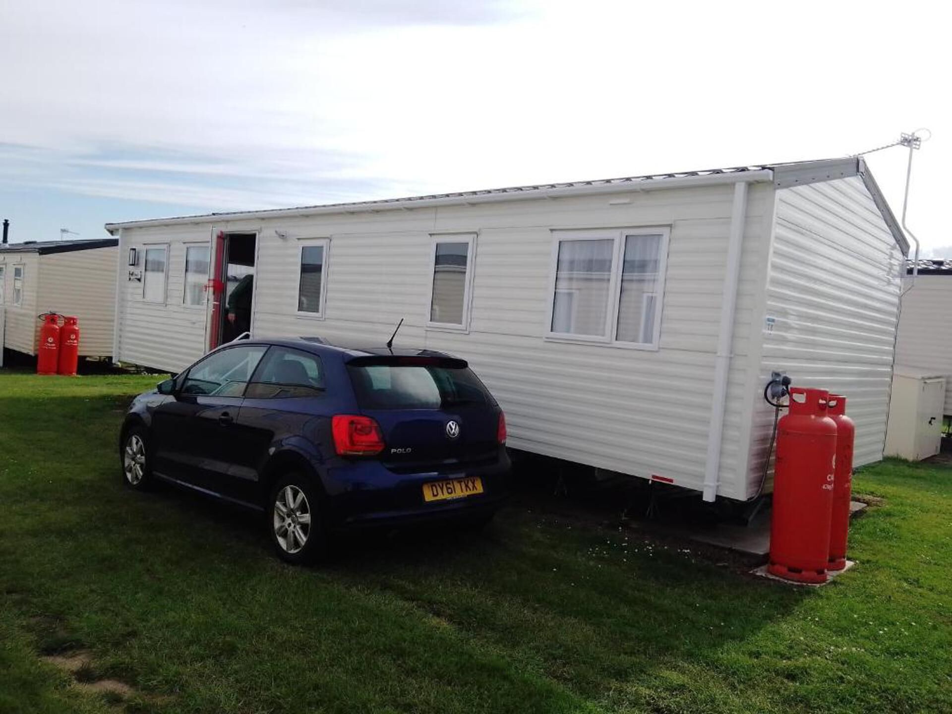 A mobile home with a Volkswagen Polo parked in front.