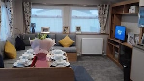 Un salon moderne avec un canapé, une table à manger dressée pour quatre personnes et un téléviseur.