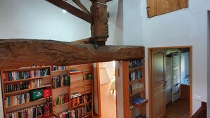 A spacious room with wooden beams, a high ceiling, and a large wooden door. - Maison de l'olivier - Rural Comfort & Relaxation (Champniers-et-Reilhac)