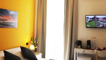A hotel room with a bed, a desk, a television, and a window with curtains.