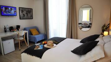 Ein Hotelzimmer mit Bett, Schreibtisch, Stuhl, Fernseher und einer Weltkarte an der Wand.