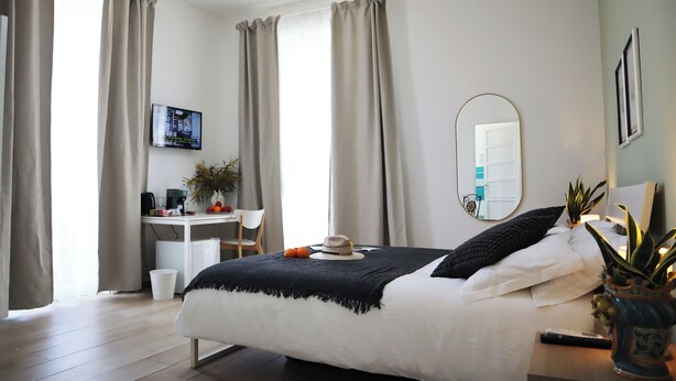 A bedroom with a bed, a desk, a chair, a television, and a mirror. - Fortuna Guest House (Syracuse)
