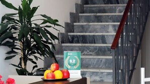A marble staircase with a wooden handrail, a potted plant, and a fruit bowl on a desk. - Fortuna Guest House (Syracuse)