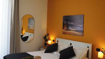 Une chambre à coucher comprenant un lit, une table de chevet, une commode, un miroir et un tableau accroché au mur.