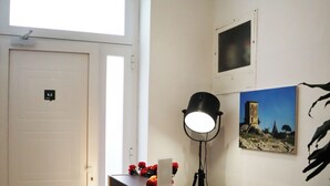 A reception desk with a modern design, a security camera above the door, and a framed picture on the wall. - Fortuna Guest House (Syracuse)