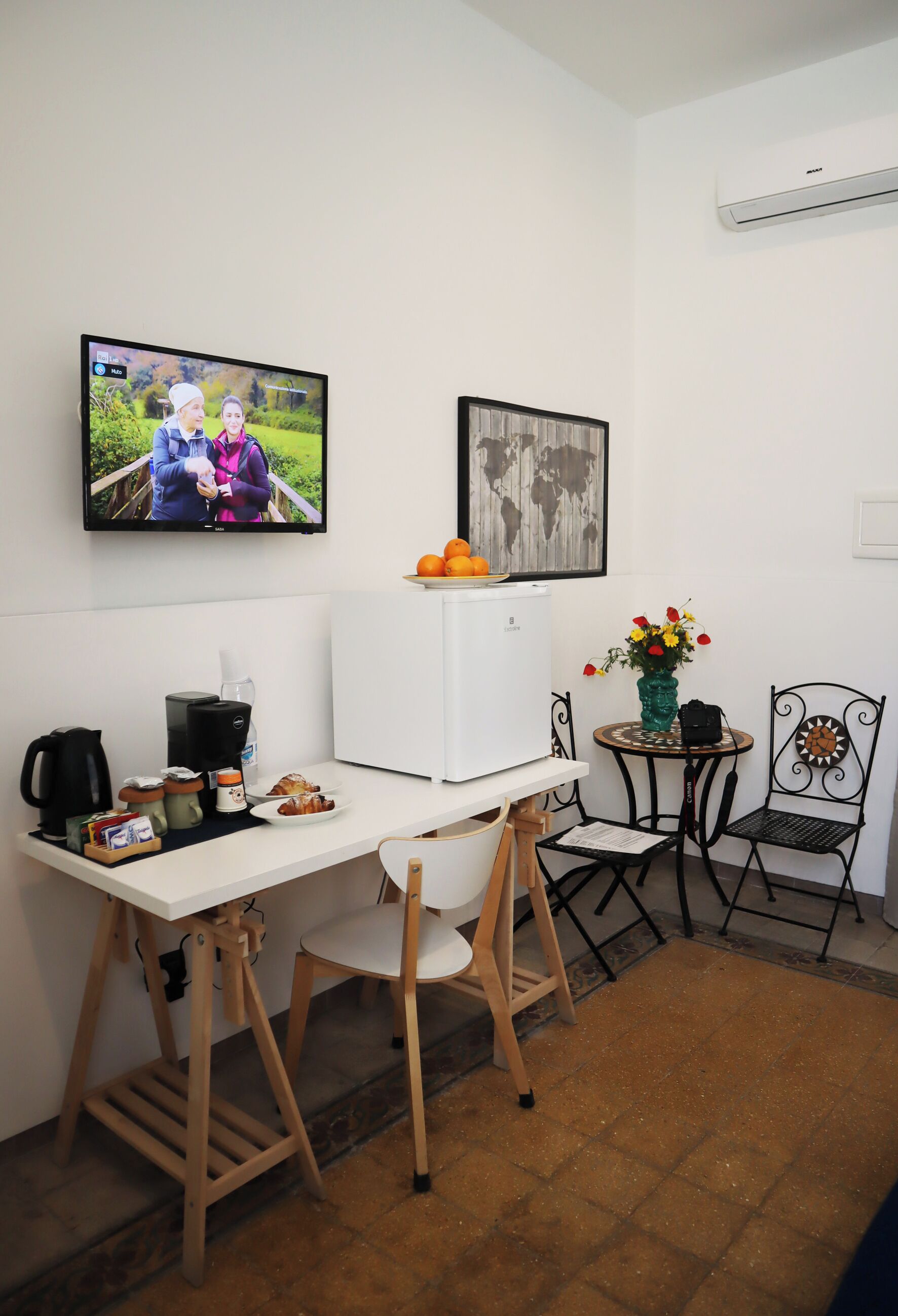 Una cocina compacta con un refrigerador blanco, una cafetera, un hervidor y una pequeña mesa con sillas.