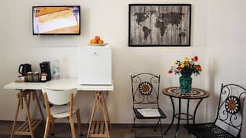Una kitchenette pequeña con un refrigerador blanco, una cafetera y un cuenco con naranjas en la encimera.