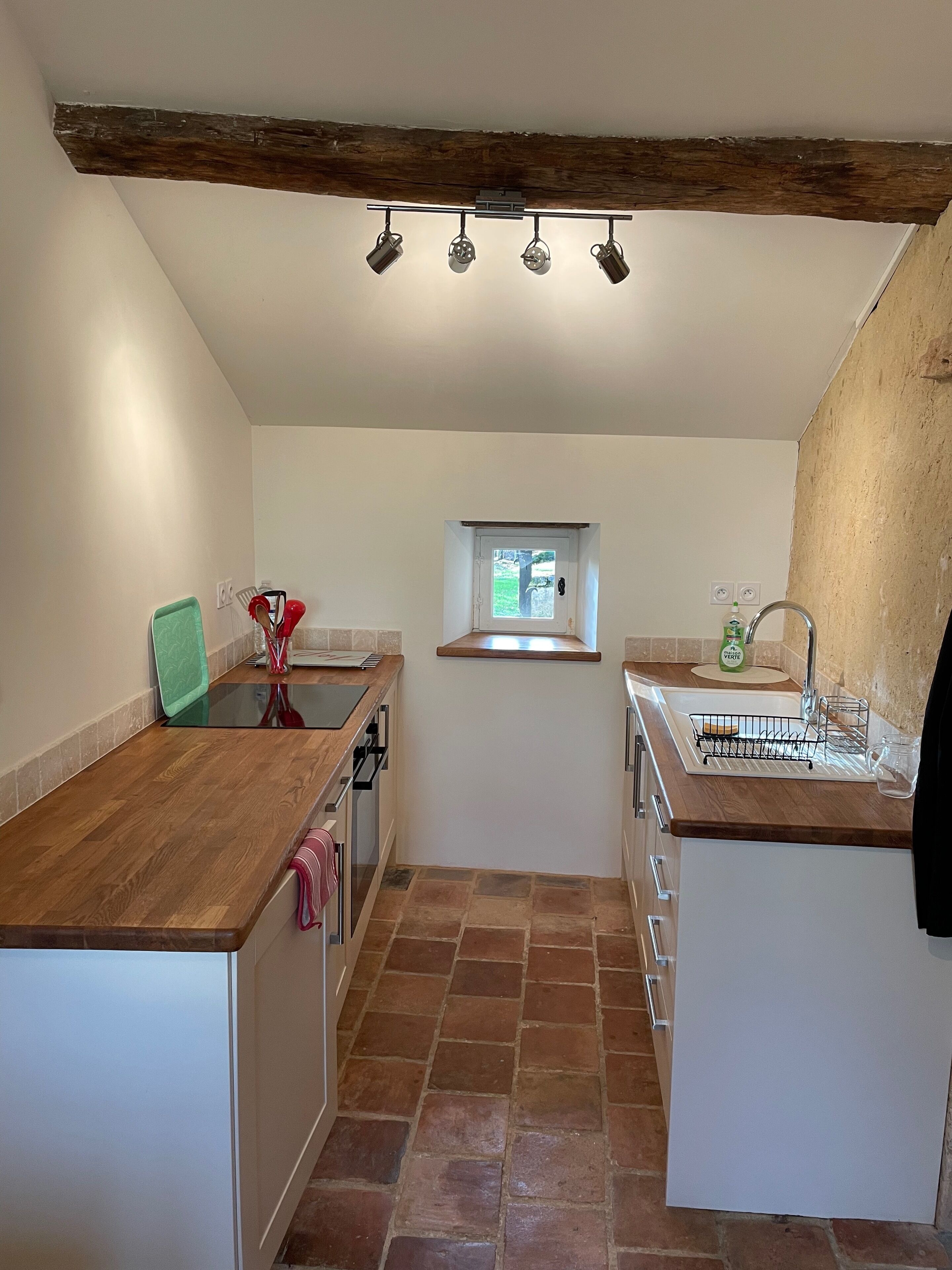 A compact kitchen with a wooden countertop, a window, and a built-in oven.