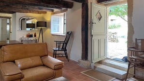 Une pièce chaleureuse avec un canapé en cuir marron, une table en bois, une chaise et un meuble blanc agrémenté d’un miroir et d’une lampe.
