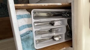 A kitchen drawer with utensils and a blue towel.