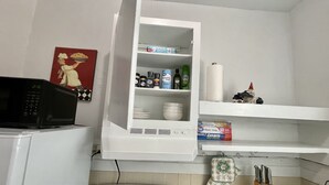A kitchen with a microwave, stove, and shelves containing kitchen items.