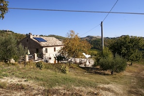 A rustic stone house with a sloped roof, solar panels, and a small porch.