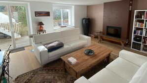 A spacious living room with a white sofa, a wooden coffee table, and a bookshelf.