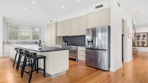 A modern kitchen with a central island, stainless steel appliances, and a view of the living area.