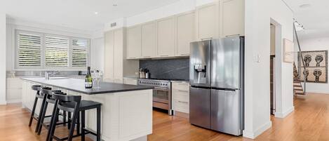 A modern kitchen with a central island, stainless steel appliances, and a view of the living area.